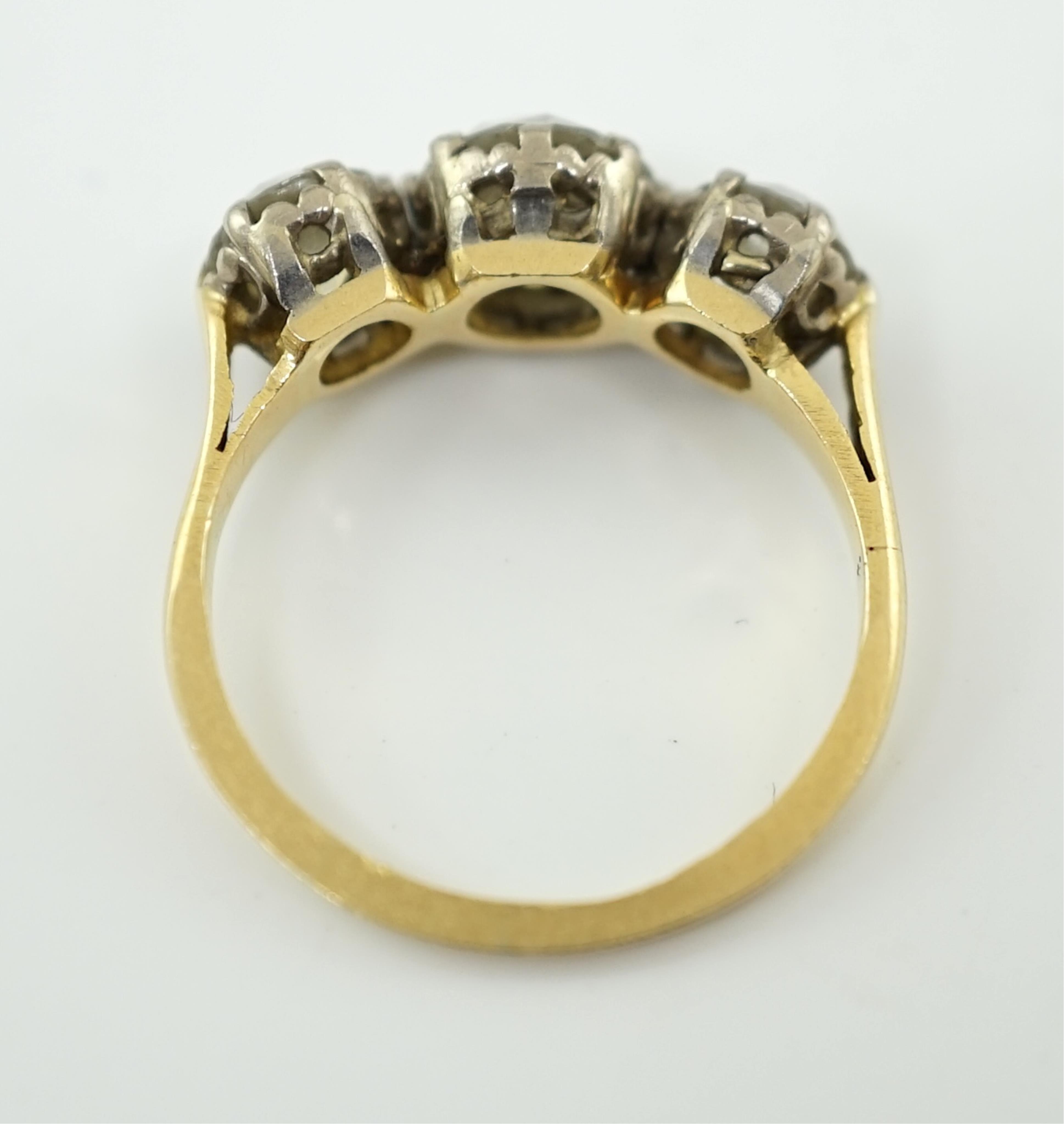 An unmarked gold and three stone diamond set ring